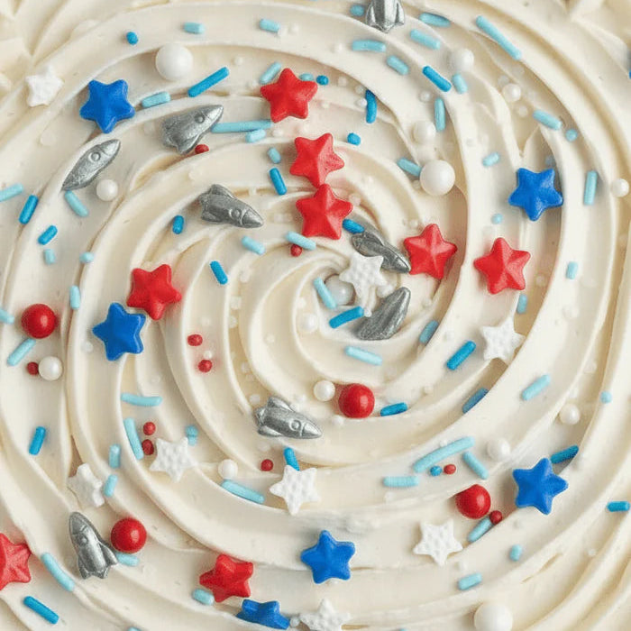 Close-up of a cake with white frosting, red, blue, and silver sprinkles.