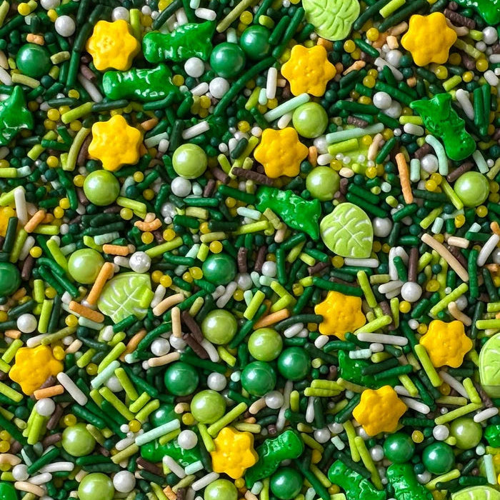 Colorful sprinkles with green, yellow, and white hues in star, leaf and dinosaur shapes.