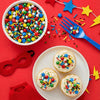 Cupcakes with colorful sprinkles on a red background with festive decorations.