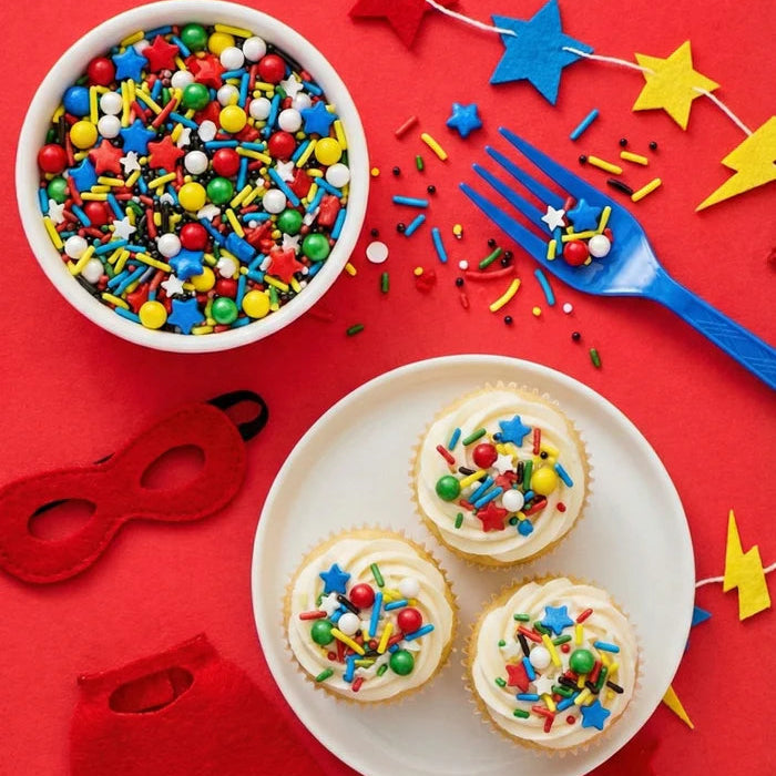 Cupcakes with colorful sprinkles on a red background with festive decorations.
