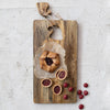 Wooden cheese board with Santa hat cutout design with a galette and cherry tarts on a light gray background 