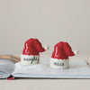 Two salt and pepper shakers shaped like Santa hats with 'naughty' and 'nice' text on a light background.