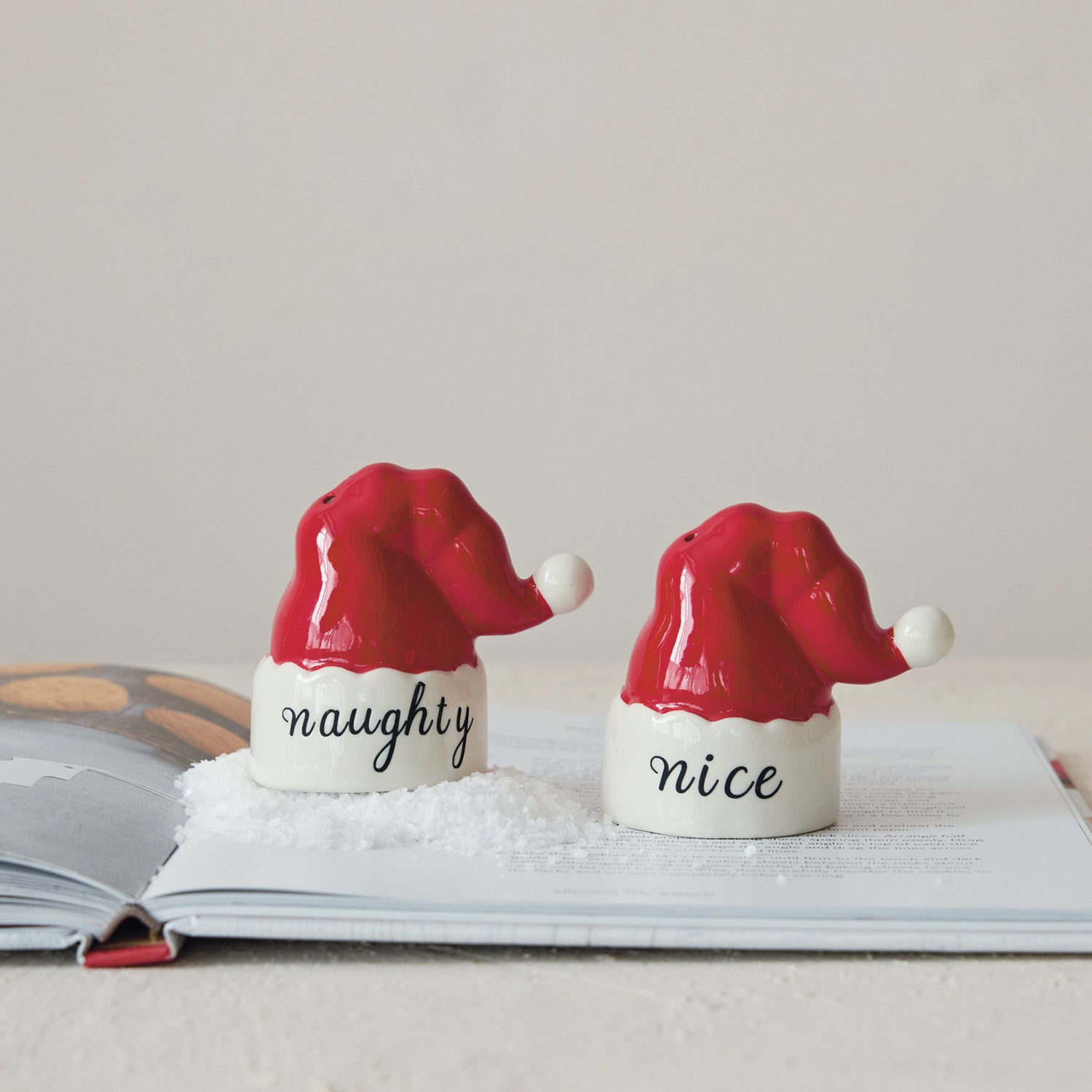 Two salt and pepper shakers shaped like Santa hats with 'naughty' and 'nice' text on a light background.