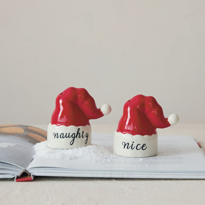 Two salt and pepper shakers shaped like Santa hats with 'naughty' and 'nice' text on a light background.