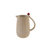 Beige pitcher with a red mushroom handle on a white background