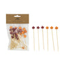 Packaged skewers with leaf decorations on a white background